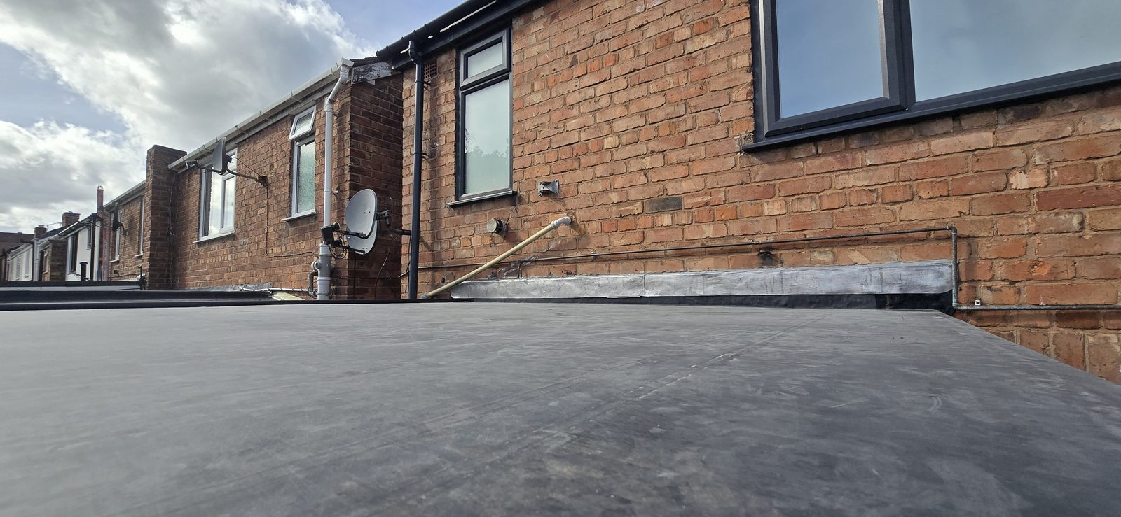 Finished EPDM rubber flat roof in Connah's Quay with lead flashing to the house wall and new black edge trims