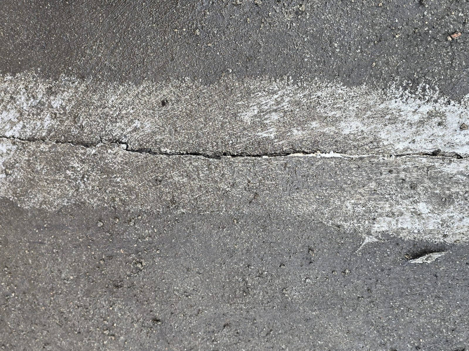 Split in roofing felt running straight through an earlier painted patch repair