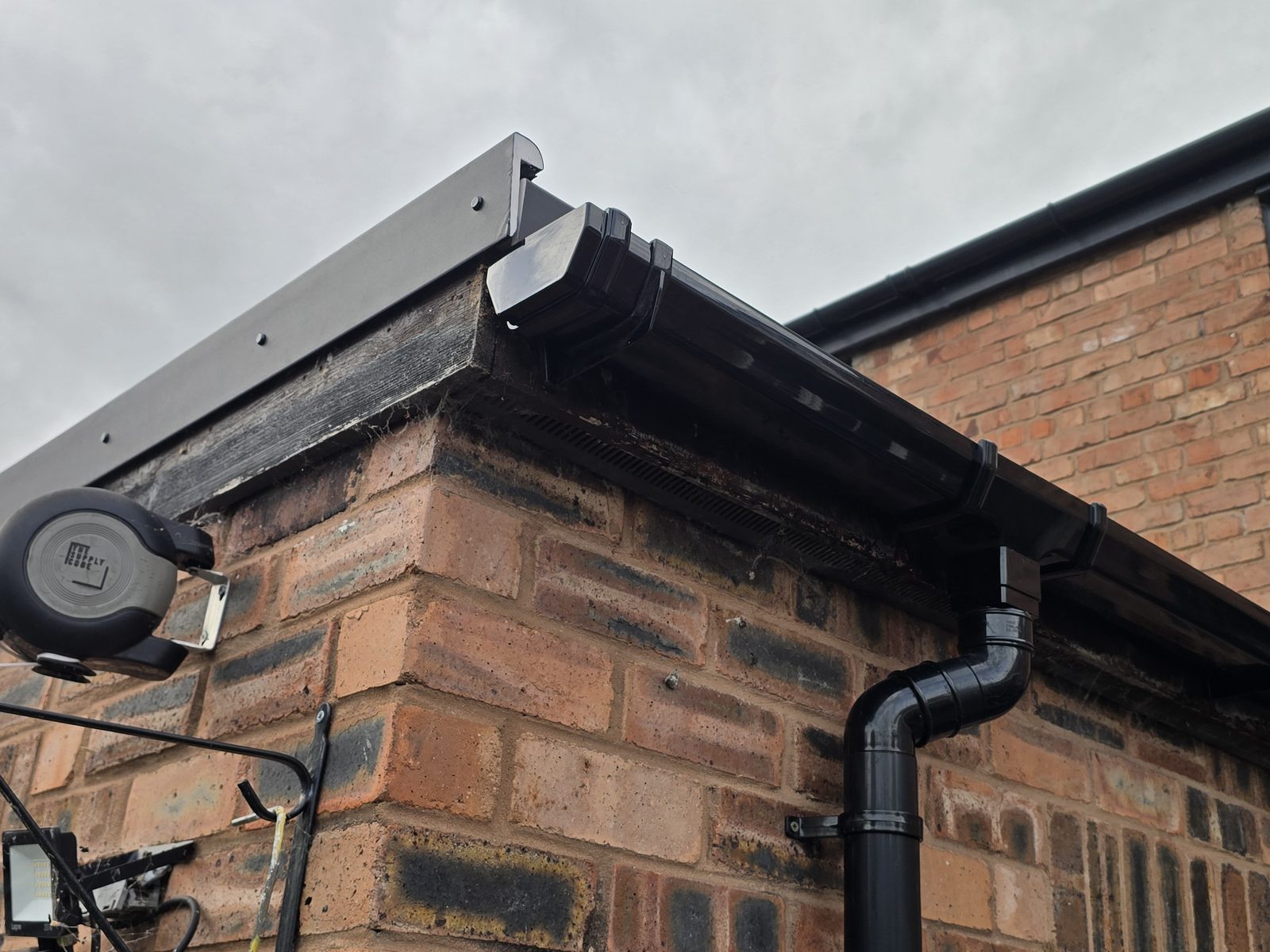 New black edge trim, gutter and downpipe on a flat roof extension in Connah's Quay