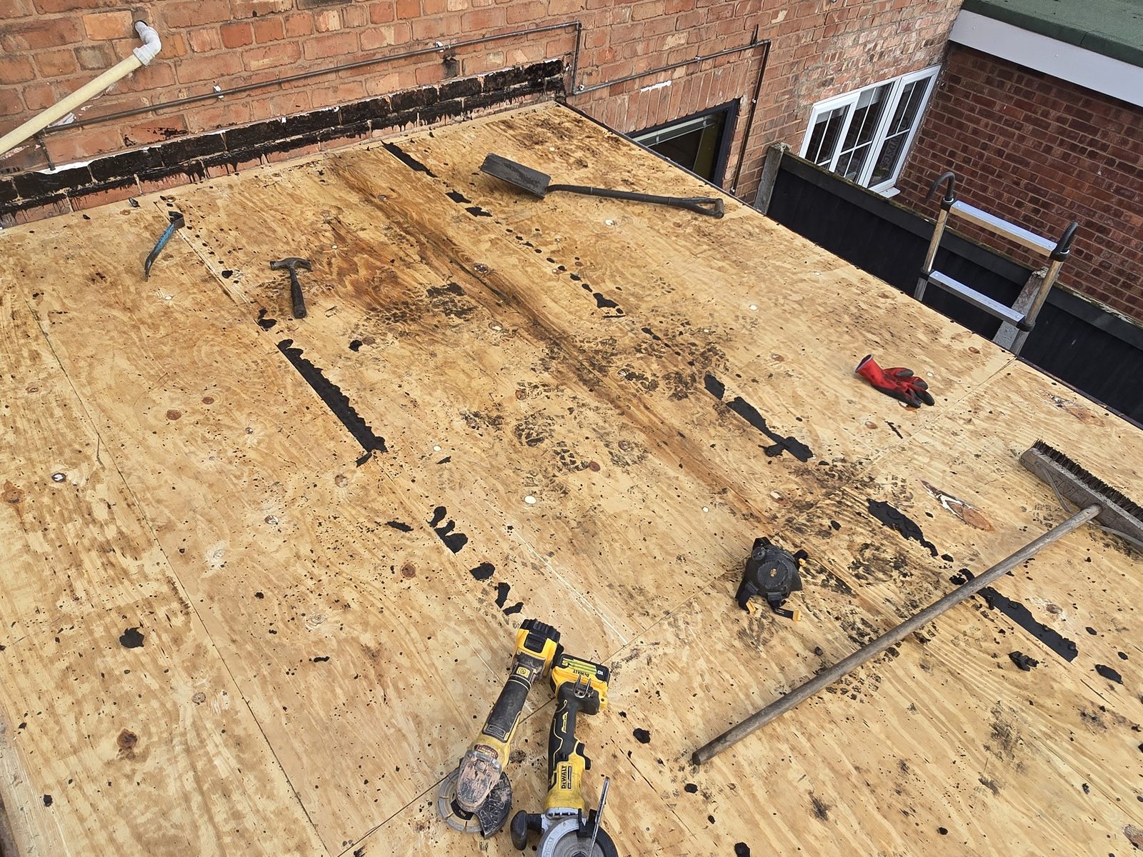 Old plywood flat roof deck exposed after the felt and chippings were stripped off