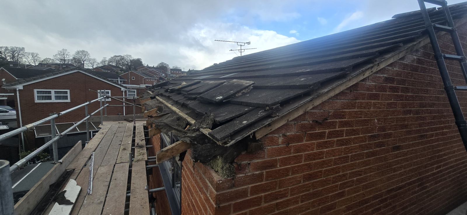 Rotten timber fascia and exposed roof edge before replacement