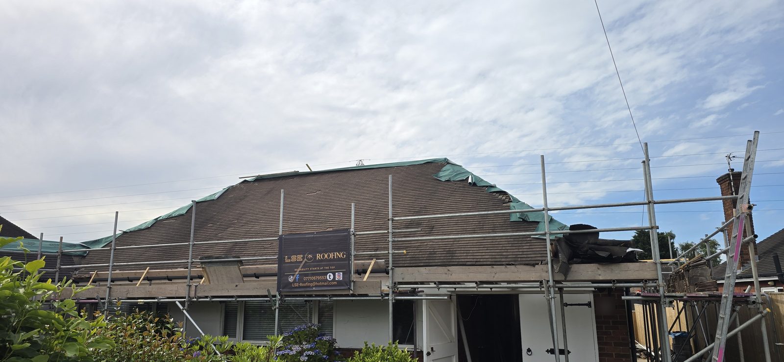 Front of the Hawarden bungalow under scaffold as the old roof covering is stripped