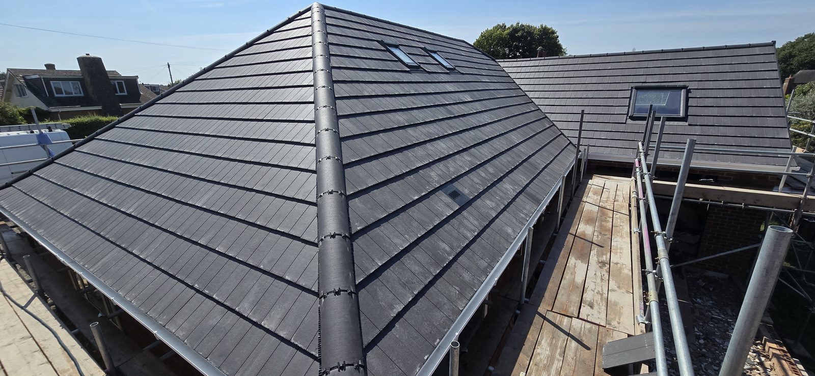 Completed hipped roof in Marley Duo Edgemere grey tiles on a bungalow in Hawarden, with the new extension roof behind