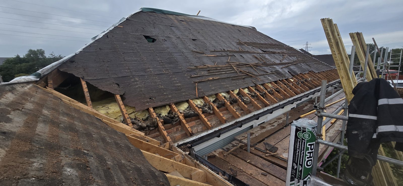 Original bitumen roofing felt perished and torn, with loft insulation exposed between the rafters
