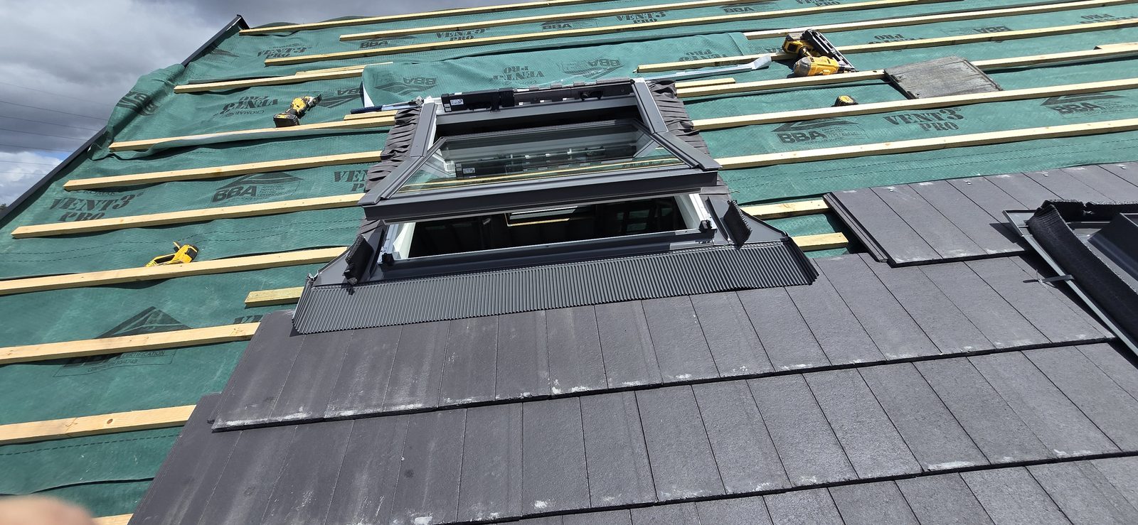New roof window being installed with its flashing kit during tiling