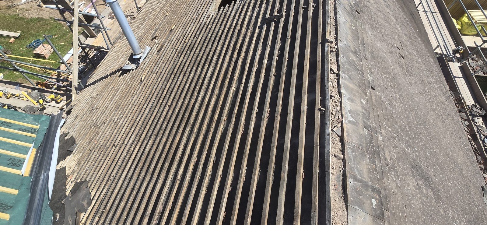 Old battens and felt stripped back alongside new breathable membrane on the next slope