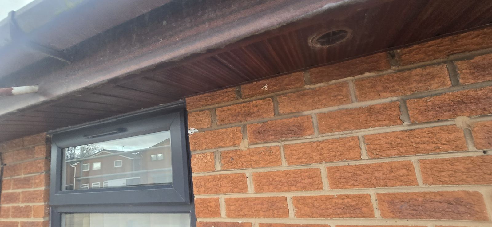 Close-up of weathered brown UPVC soffit and vent before fascia replacement in Wrexham